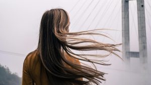 Vrouw met lang haar staat buiten terwijl haar haar door de wind waait