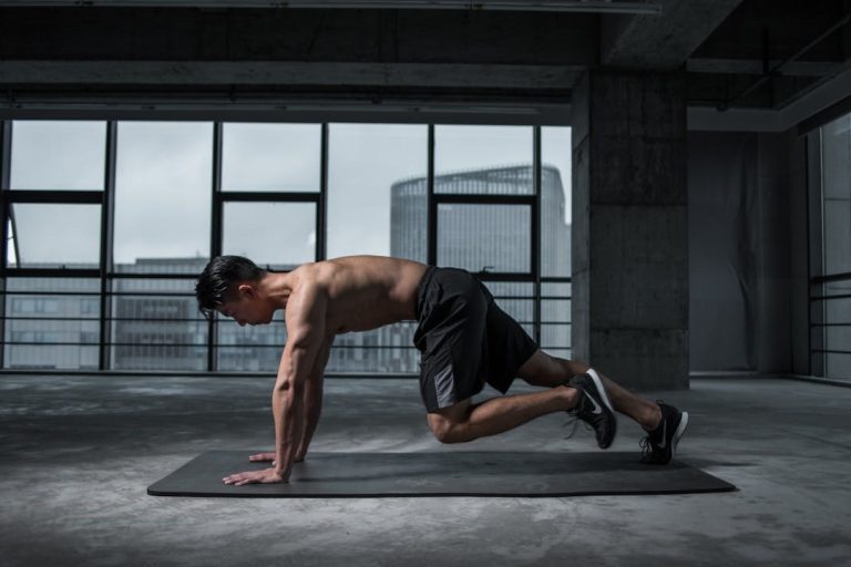 Man traint zijn core met mountain climbers op een mat in een lege, industriële gymruimte – focus op terugval voorkomen.