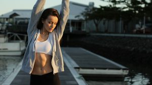 Sportieve vrouw rekt zich uit op steiger als voorbereiding op zuurstoftraining en herstel